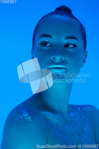 Image of Handsome woman\'s portrait isolated on blue studio background in neon light, monochrome