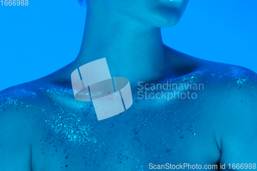 Image of Handsome woman\'s close up portrait isolated on blue studio background in neon light, monochrome