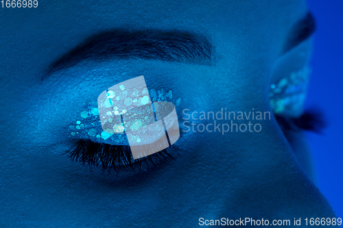 Image of Handsome woman\'s close up portrait isolated on blue studio background in neon light, monochrome