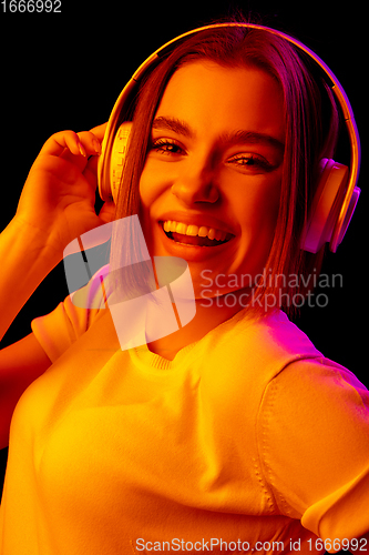 Image of Caucasian woman\'s portrait isolated on black studio background in multicolored neon light