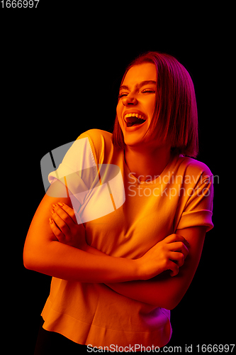 Image of Caucasian woman\'s portrait isolated on black studio background in multicolored neon light