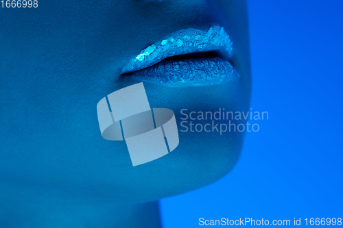 Image of Handsome woman\'s close up portrait isolated on blue studio background in neon light, monochrome