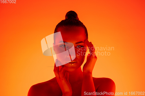 Image of Handsome woman\'s portrait isolated on orange gradient studio background in neon light, monochrome