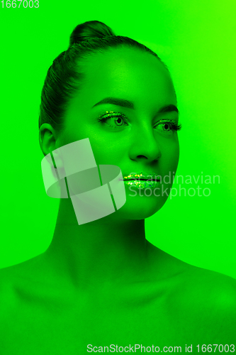 Image of Handsome woman\'s portrait isolated on green studio background in neon light, monochrome