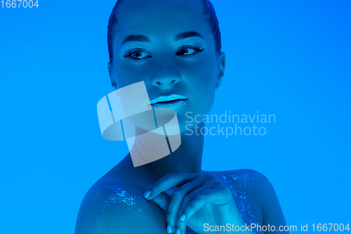 Image of Handsome woman\'s portrait isolated on blue studio background in neon light, monochrome