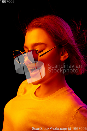 Image of Caucasian woman\'s portrait isolated on black studio background in multicolored neon light