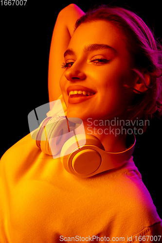 Image of Caucasian woman\'s portrait isolated on black studio background in multicolored neon light