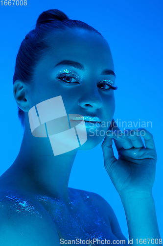 Image of Handsome woman\'s portrait isolated on blue studio background in neon light, monochrome