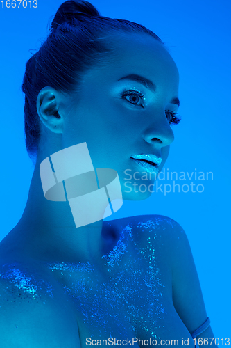 Image of Handsome woman\'s portrait isolated on blue studio background in neon light, monochrome