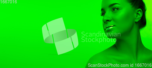 Image of Handsome woman\'s portrait isolated on green studio background in neon light, monochrome
