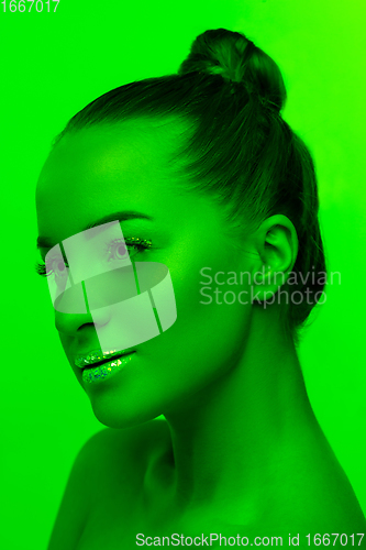 Image of Handsome woman\'s portrait isolated on green studio background in neon light, monochrome