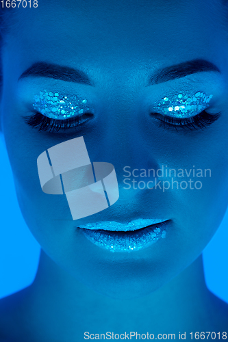 Image of Handsome woman\'s portrait isolated on blue studio background in neon light, monochrome