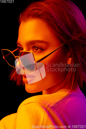 Image of Caucasian woman\'s portrait isolated on black studio background in multicolored neon light