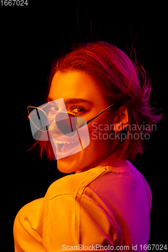 Image of Caucasian woman\'s portrait isolated on black studio background in multicolored neon light