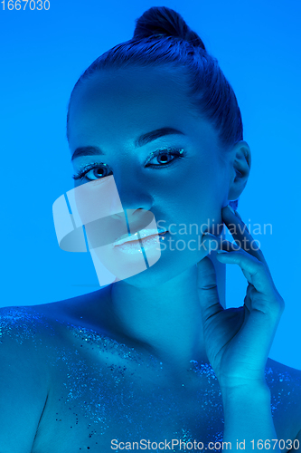 Image of Handsome woman\'s portrait isolated on blue studio background in neon light, monochrome