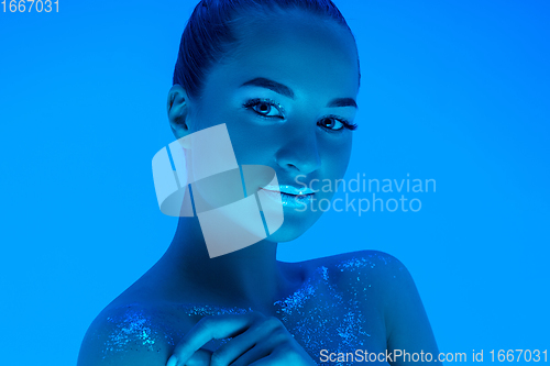 Image of Handsome woman\'s portrait isolated on blue studio background in neon light, monochrome