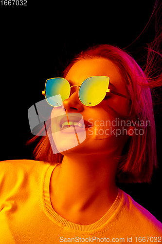 Image of Caucasian woman\'s portrait isolated on black studio background in multicolored neon light