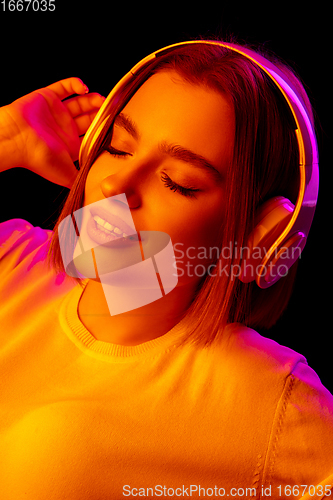 Image of Caucasian woman\'s portrait isolated on black studio background in multicolored neon light