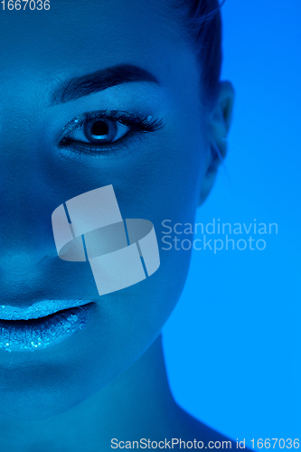 Image of Handsome woman\'s portrait isolated on blue studio background in neon light, monochrome