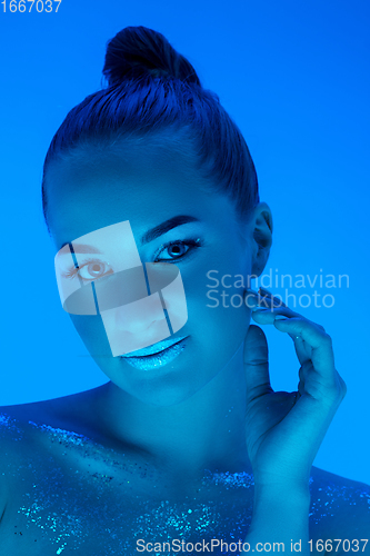 Image of Handsome woman\'s portrait isolated on blue studio background in neon light, monochrome