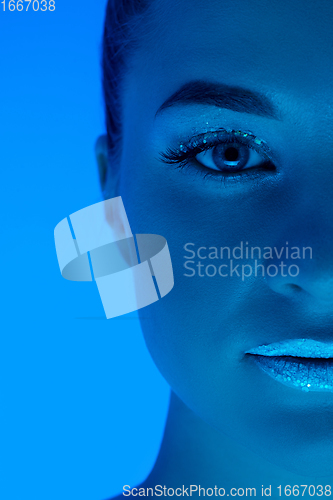 Image of Handsome woman\'s portrait isolated on blue studio background in neon light, monochrome