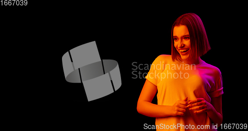 Image of Caucasian woman\'s portrait isolated on black studio background in multicolored neon light