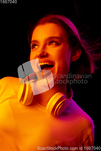 Image of Caucasian woman\'s portrait isolated on black studio background in multicolored neon light