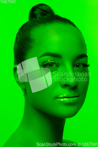 Image of Handsome woman\'s portrait isolated on green studio background in neon light, monochrome