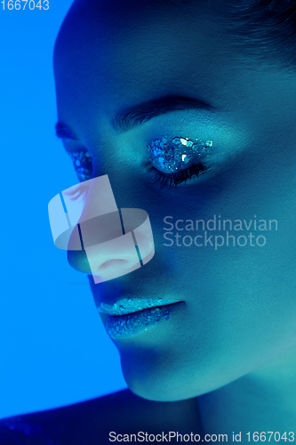 Image of Handsome woman\'s portrait isolated on blue studio background in neon light, monochrome