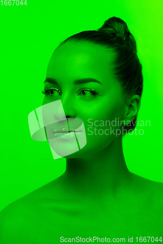 Image of Handsome woman\'s portrait isolated on green studio background in neon light, monochrome