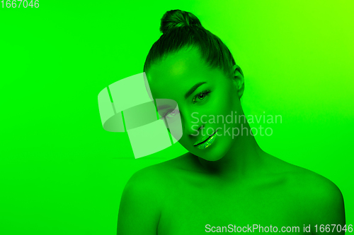 Image of Handsome woman\'s portrait isolated on green studio background in neon light, monochrome