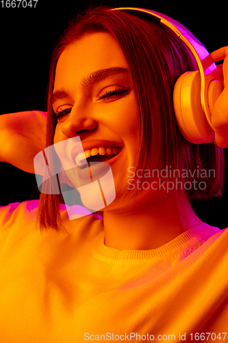Image of Caucasian woman\'s portrait isolated on black studio background in multicolored neon light