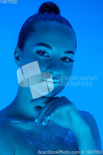 Image of Handsome woman\'s portrait isolated on blue studio background in neon light, monochrome