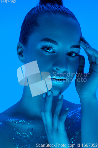 Image of Handsome woman\'s portrait isolated on blue studio background in neon light, monochrome