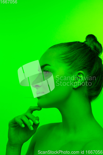 Image of Handsome woman\'s portrait isolated on green studio background in neon light, monochrome