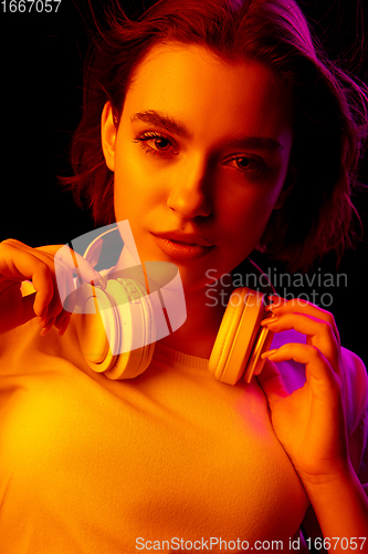 Image of Caucasian woman\'s portrait isolated on black studio background in multicolored neon light