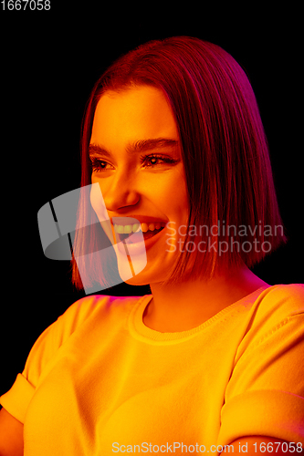 Image of Caucasian woman\'s portrait isolated on black studio background in multicolored neon light