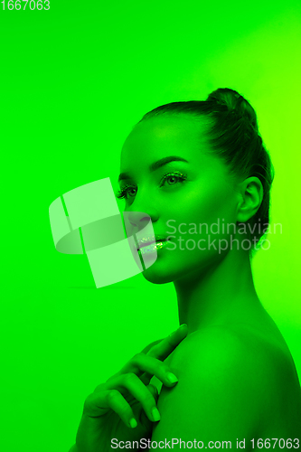 Image of Handsome woman\'s portrait isolated on green studio background in neon light, monochrome