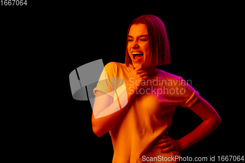 Image of Caucasian woman\'s portrait isolated on black studio background in multicolored neon light