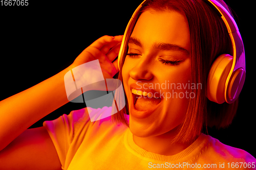 Image of Caucasian woman\'s portrait isolated on black studio background in multicolored neon light