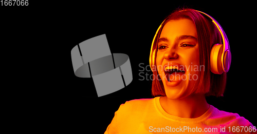 Image of Caucasian woman\'s portrait isolated on black studio background in multicolored neon light