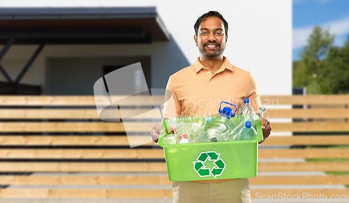 Image of smiling young indian man sorting plastic waste