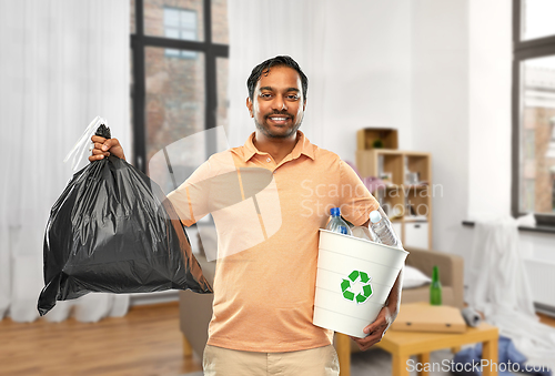 Image of smiling indian man sorting paper and plastic waste