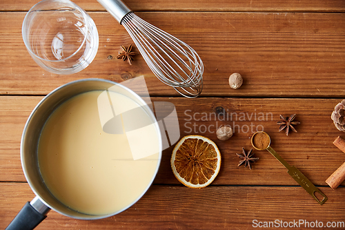 Image of pot with eggnog, ingredients and spices on wood