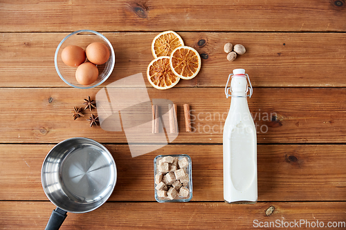 Image of ingredients for eggnog, sugar and spices on wood