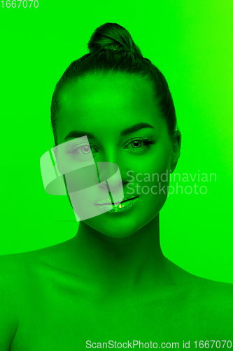 Image of Handsome woman\'s portrait isolated on green studio background in neon light, monochrome