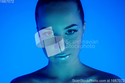 Image of Handsome woman\'s portrait isolated on blue studio background in neon light, monochrome