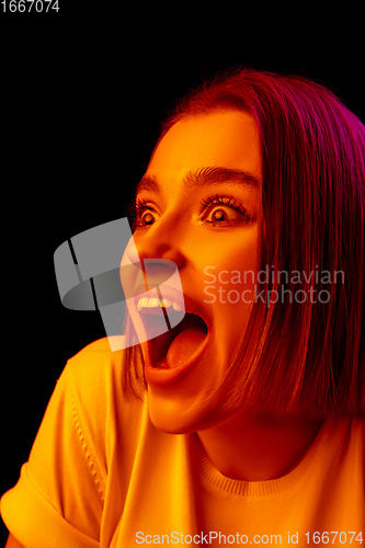 Image of Caucasian woman\'s portrait isolated on black studio background in multicolored neon light