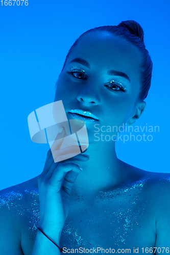 Image of Handsome woman\'s portrait isolated on blue studio background in neon light, monochrome