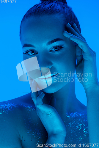 Image of Handsome woman\'s portrait isolated on blue studio background in neon light, monochrome